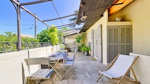 Un balcon avec une table dressée pour le repas, deux chaises et un fauteuil.