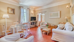 Un salon confortable avec un canapé, des fauteuils, un téléviseur et une table sur laquelle se trouve une lampe.