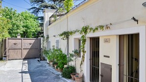 Une rue étroite bordée d’un immeuble dont l’entrée est fermée par un portail, agrémenté de plantes en pot et d’une enseigne indiquant « La Climatite ».