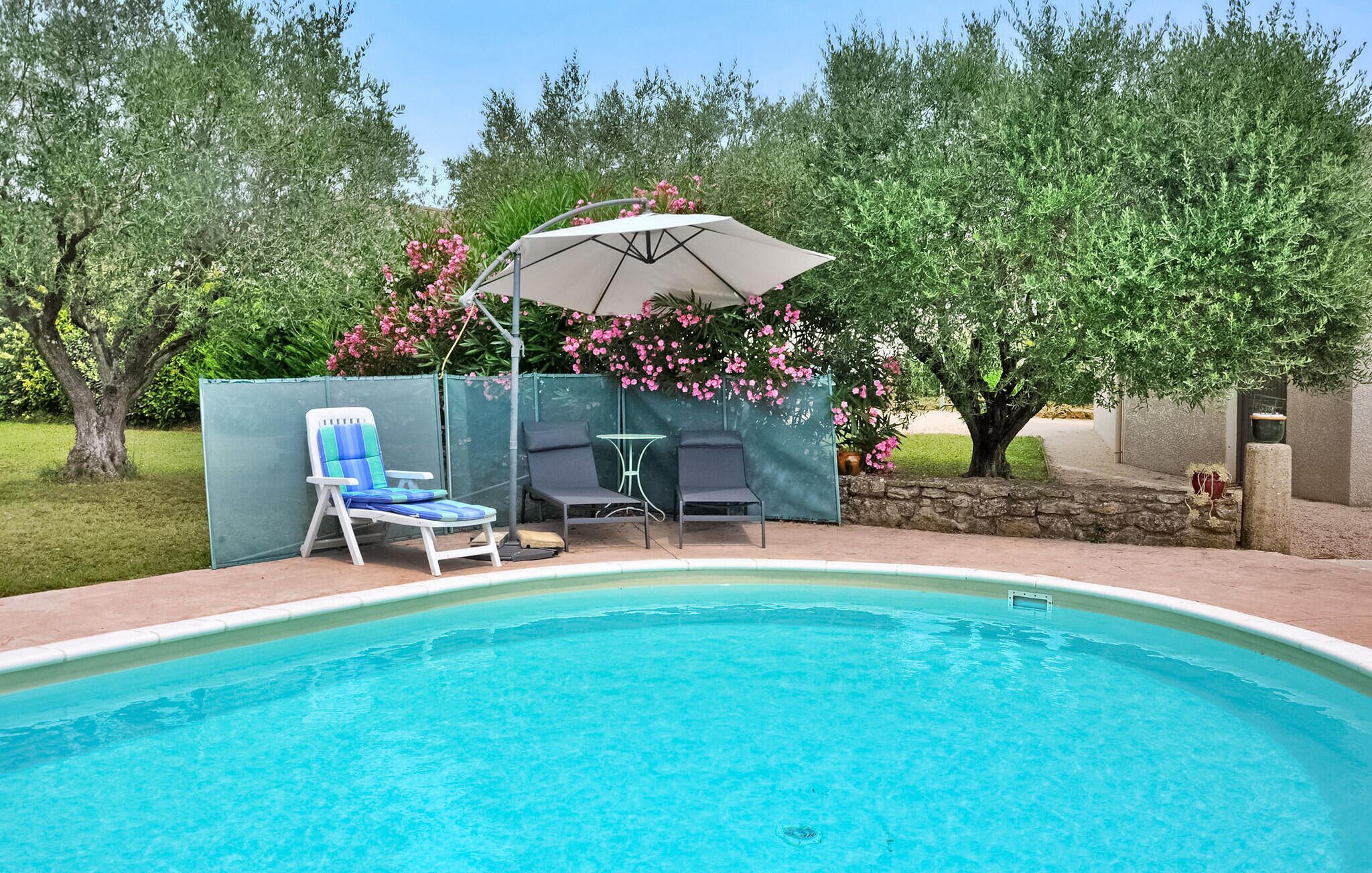 A swimming pool with a lounge area, including a covered umbrella and two chairs.