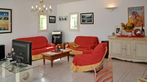 A living room with a red sofa set, a coffee table, a television, and a cabinet with decorative items.