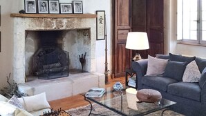 A living room with a fireplace, a sofa, a glass coffee table, and a lamp.