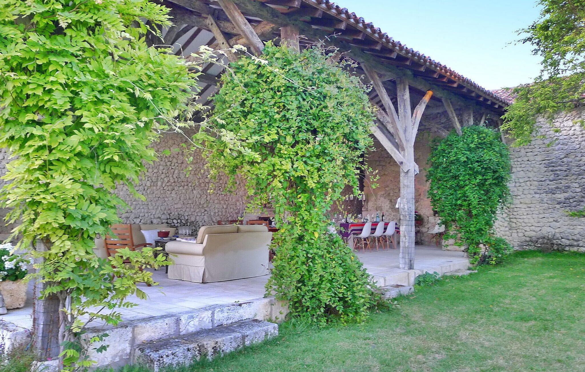 A covered outdoor seating area with stone walls and greenery.