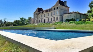 A large, historic building with a swimming pool in front.