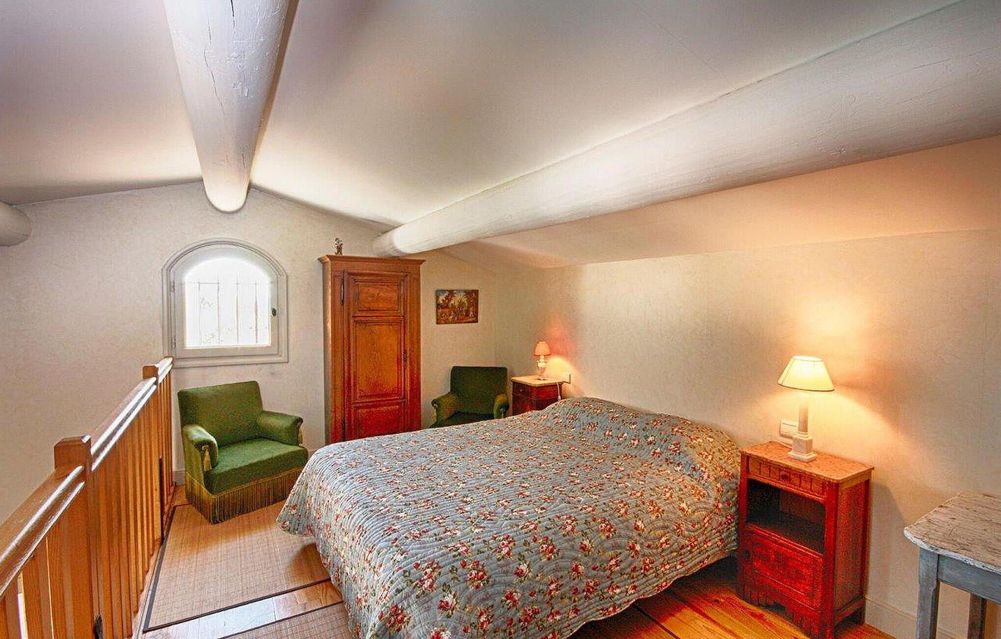 Una camera da letto con un letto, una sedia, una scrivania, una lampada e una finestra.