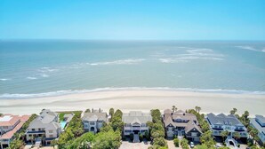 Un quartier résidentiel situé sur la côte, avec des propriétés en bord de mer, notamment des maisons à étages et une demeure imposante dotée d’une grande véranda.