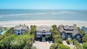 Une propriété située en bord de mer, comprenant une grande maison, une piscine et une vue sur la plage.