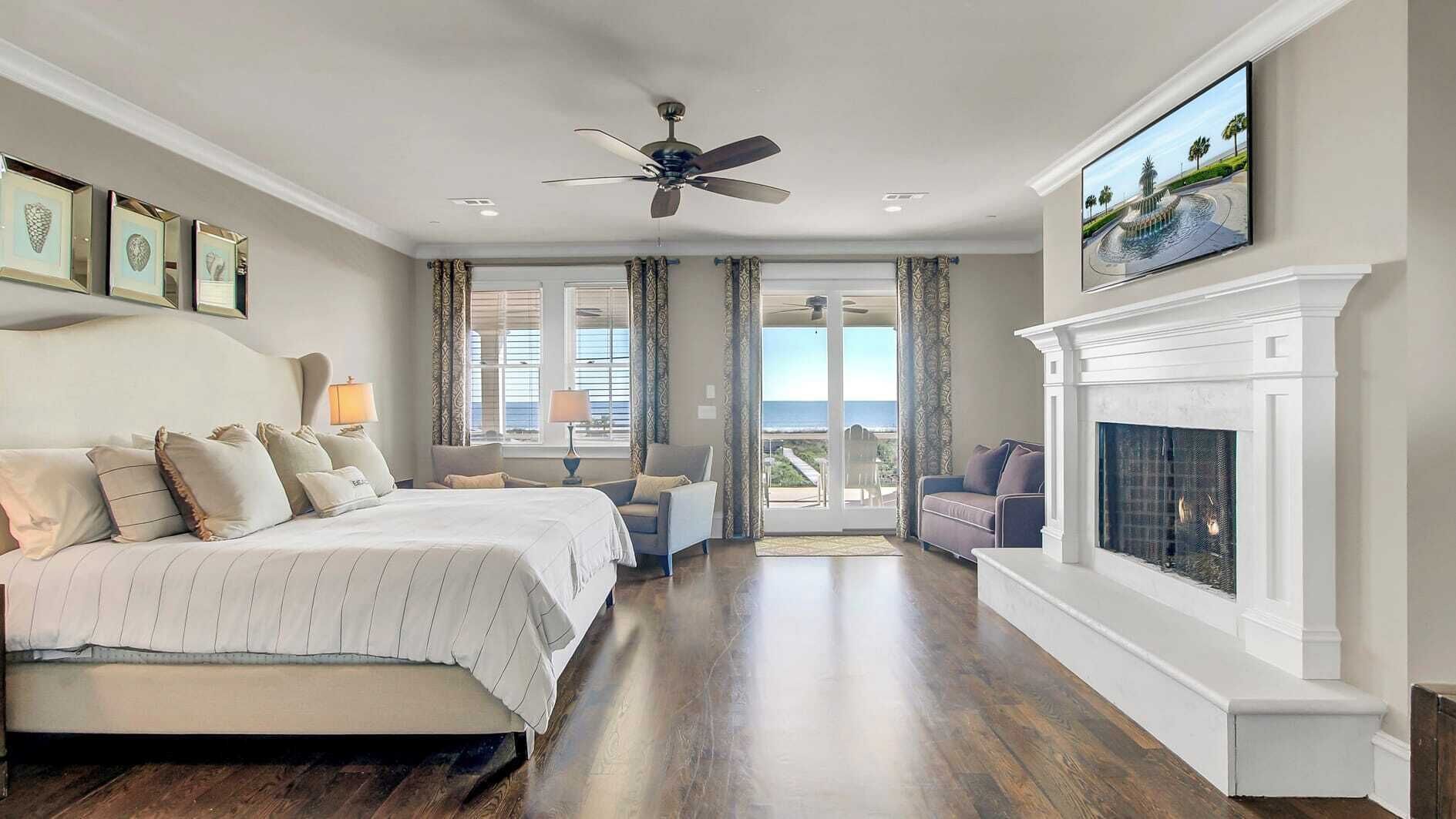 A spacious bedroom with a large bed, a fireplace, and a view of the ocean.