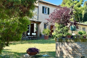 Une maison avec un jardin, du mobilier d’extérieur et un mur en pierre.