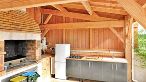 A rustic kitchen with a brick fireplace, wooden beams, and a small refrigerator. - Awesome home in Cours De Pile (Cours De Pile)