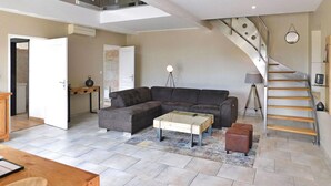 A spacious living area with a sectional sofa, a coffee table, and a staircase leading to an upper floor. - Awesome home in Cours De Pile (Cours De Pile)