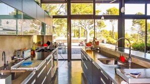 Una cocina moderna con electrodomésticos de acero inoxidable, ventanas amplias y vistas al exterior.