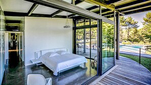 Un dormitorio moderno con una cama grande, una pared de vidrio y vistas al exterior.