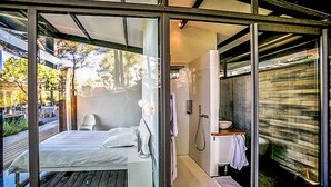 Un dormitorio moderno con una puerta de vidrio que da al baño.