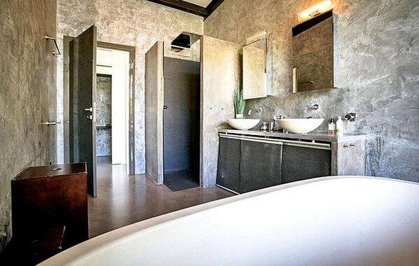 A modern bathroom with a large bathtub, two sinks, and a walk-in shower.