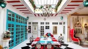 A dining area with a checkered floor, a central table with a white tablecloth, and red and blue chairs. - The Royal Hermitage (Jaipur)