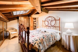 A bedroom with a wooden bed, a wicker chair, a bookshelf, and a skylight.