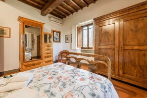 A bedroom with a wooden bed frame, a large wardrobe, a dresser, and a mirror.