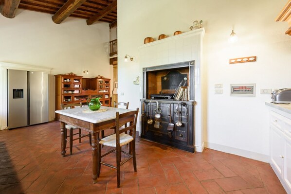 A kitchen with a wooden table, chairs, a stove, and cabinets.