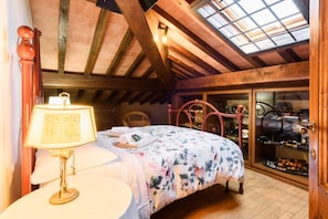 A bedroom with a bed, a lamp, a wooden ceiling, and a window.