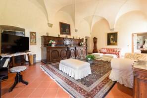 A living room with a piano, television, and a large cabinet with decorative items.
