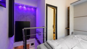 Ett modernt hotellrum med en säng, en väggmonterad TV och en badrumsdörr.
