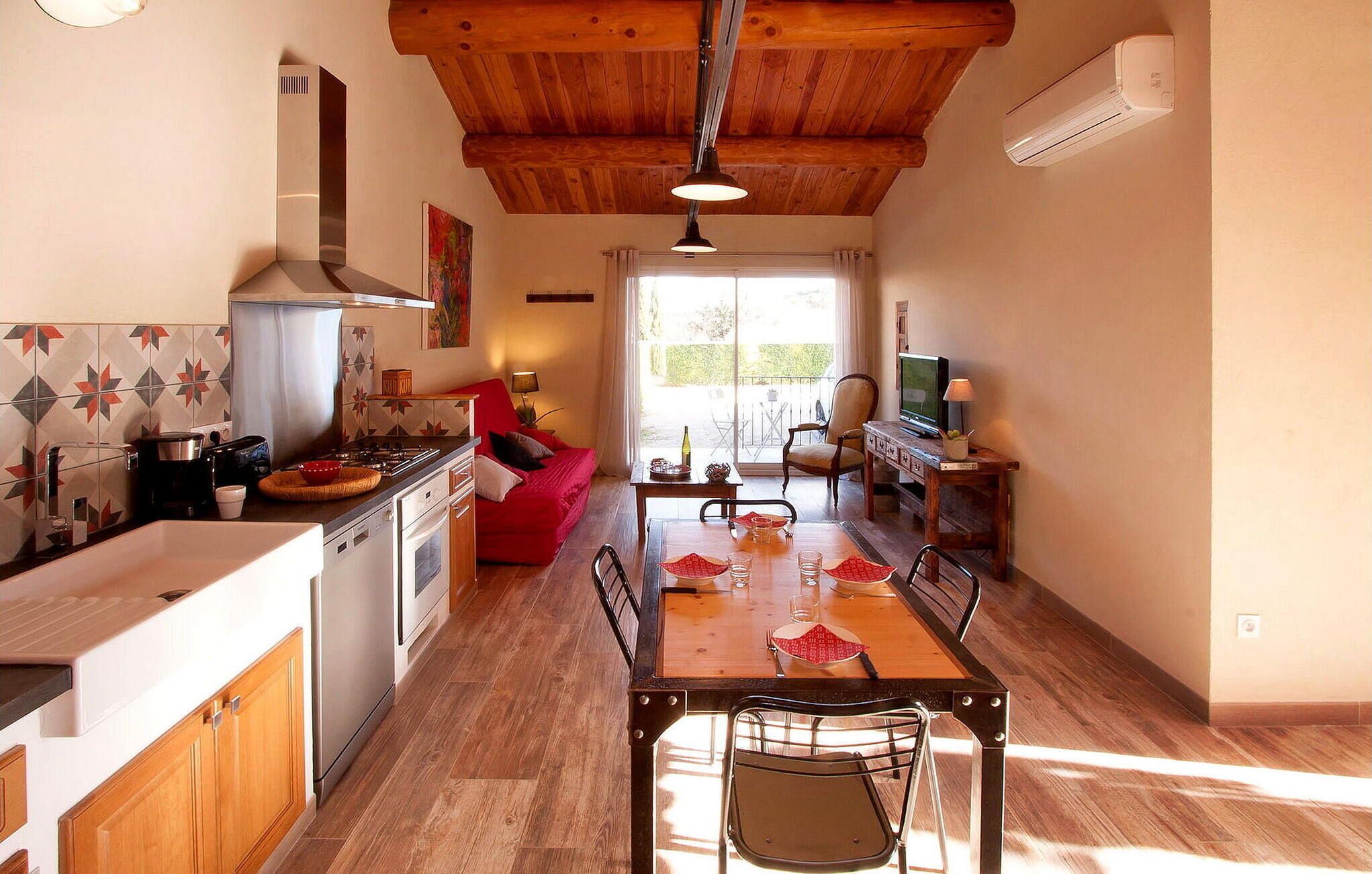 Una cocina compacta con armarios de madera, una mesa de comedor con sillas, un sofá y un televisor.