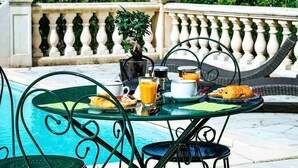 A table with breakfast items, a glass of orange juice, and a small plant.