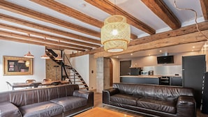 A modern living room with leather sofas, a wooden coffee table, and a staircase leading to an upper level.
