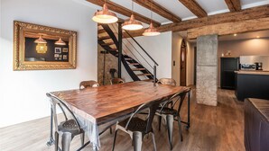 A dining area with a wooden table and chairs, a staircase, and a kitchen area with modern appliances.