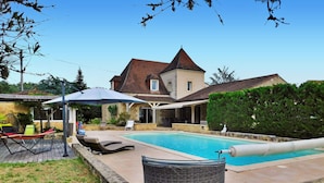 Un jardin avec une piscine, des chaises longues et une pergola.