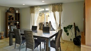 Un coin repas avec une table et des chaises, une bibliothèque et une plante.