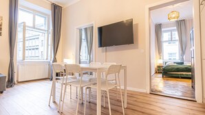 Ein Zimmer mit Esstisch und Stühlen, einem Flachbildfernseher und einem Bett im angrenzenden Raum.