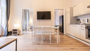 Eine moderne Küche mit weißen Schränken, einem Flachbildfernseher und einem Essbereich mit Tisch und Stühlen.