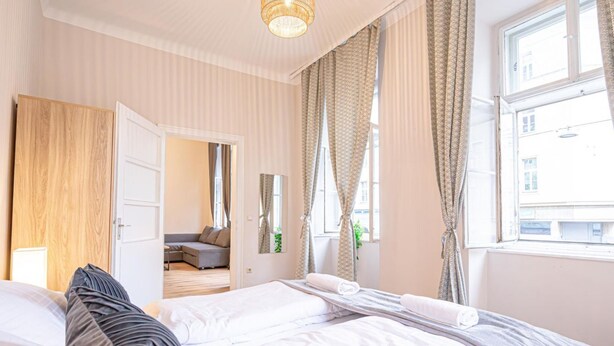 Ein Hotelzimmer mit Bett, Schrank, Spiegel und einem Fenster mit Vorhängen.