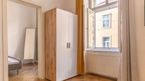 Une pièce avec une armoire en bois, un radiateur et une fenêtre avec des rideaux.