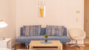 Un salon avec un canapé, une table basse, une lampe, un fauteuil et une petite plante.