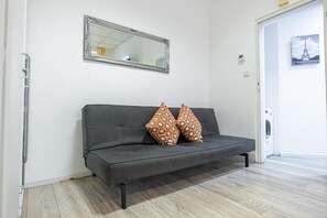 A grey sofa with patterned cushions, a mirror, and a door leading to a laundry area. - Modern Apart. - Huge Longstay discount (Vienna)