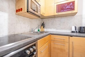 Cozinha com micro-ondas, pia e armários de madeira.