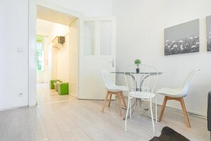 A modern dining area with a glass table, white chairs, and a small potted plant.