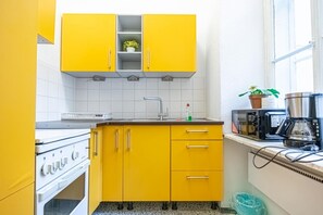 Una cocina con armarios amarillos, una estufa blanca, un microondas y una cafetera.