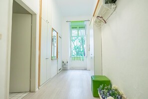 A hallway with a green bench, a window with a green curtain, and a door on the left.