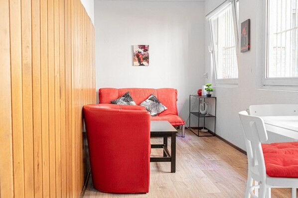Un salon moderne avec un canapé rouge, une petite table et une chaise blanche.