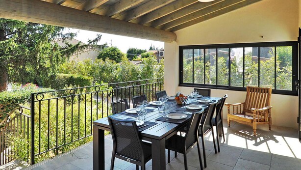 A dining area with a table set for four, surrounded by chairs, a wooden bench, and a view of a garden through large windows. - Pet friendly home in Moulès (Moulès)