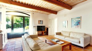 Un salon comprenant un canapé, une table basse, un téléviseur et une porte donnant sur l’extérieur.