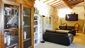 Una sala de estar con un aparador de madera, un sofá de cuero negro, una pared de piedra y un televisor de pantalla plana montado.
