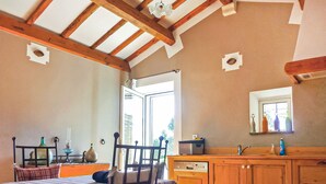 Una habitación con una cama, una silla de madera, un armario de madera, una ventana y una puerta.