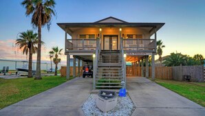 A two-story house with a balcony, a staircase, and a sign reading 'SEA THERAPY'. - Private Pool, in Golf Cart Zone, Golf Cart for Rent Sea Therapy by Avantstay (Port Aransas)