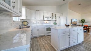 A modern kitchen with white cabinetry, a central island, and a microwave. - Private Pool, in Golf Cart Zone, Golf Cart for Rent Sea Therapy by Avantstay (Port Aransas)