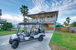 Ein Golfwagen vor einem zweistöckigen Haus mit Balkon und einem Schild mit der Aufschrift 'SEA THERAPY'.